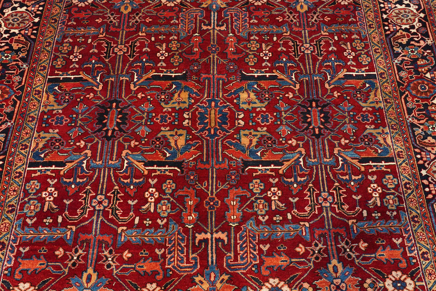 North West Persian Karadja hand-knotted carpet, deep red field decorated with an all-over lattice design of elongated geometric devices interspersed with rosettes and angular palmettes, enclosed by a dark indigo main border of stylized floral and geometric motifs between multiple guard stripes, with cotton fringe ends 