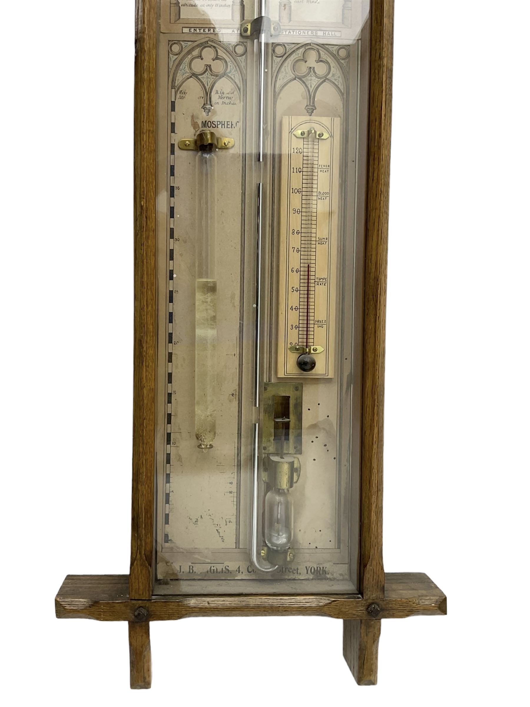 Admiral Fitzroy - Early 20th century Fitzroy barometer in a glazed gothic influenced oak case with chamfered uprights and top and base panels, full length paper scales with Fitzroy's observations and predictions, mercury bulb cistern, storm glass, spirit thermometer and brass sliding vernier pointers. Retailed by Inglis & Son, Coney Street, York.
