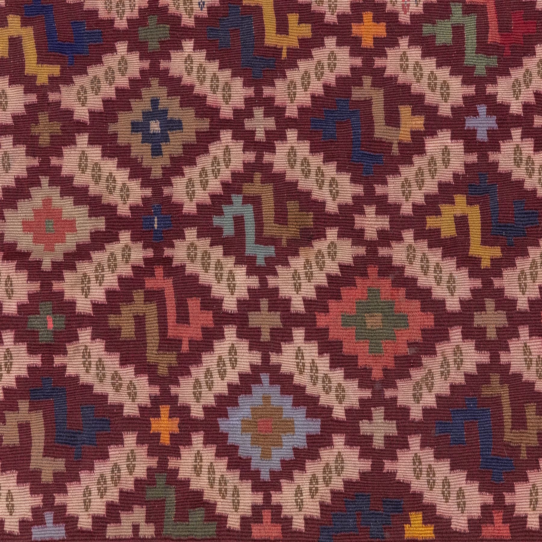 South West Persian Qashgai flatweave kilim, field decorated with a repeating diagonal lattice of stepped lozenges and angular hooked motifs, interspersed with small tribal devices, woven is shade of madder red, soft pink, indigo blue, ochre, and olive green, framed by a narrow geometric border and contrasting guard stripes 