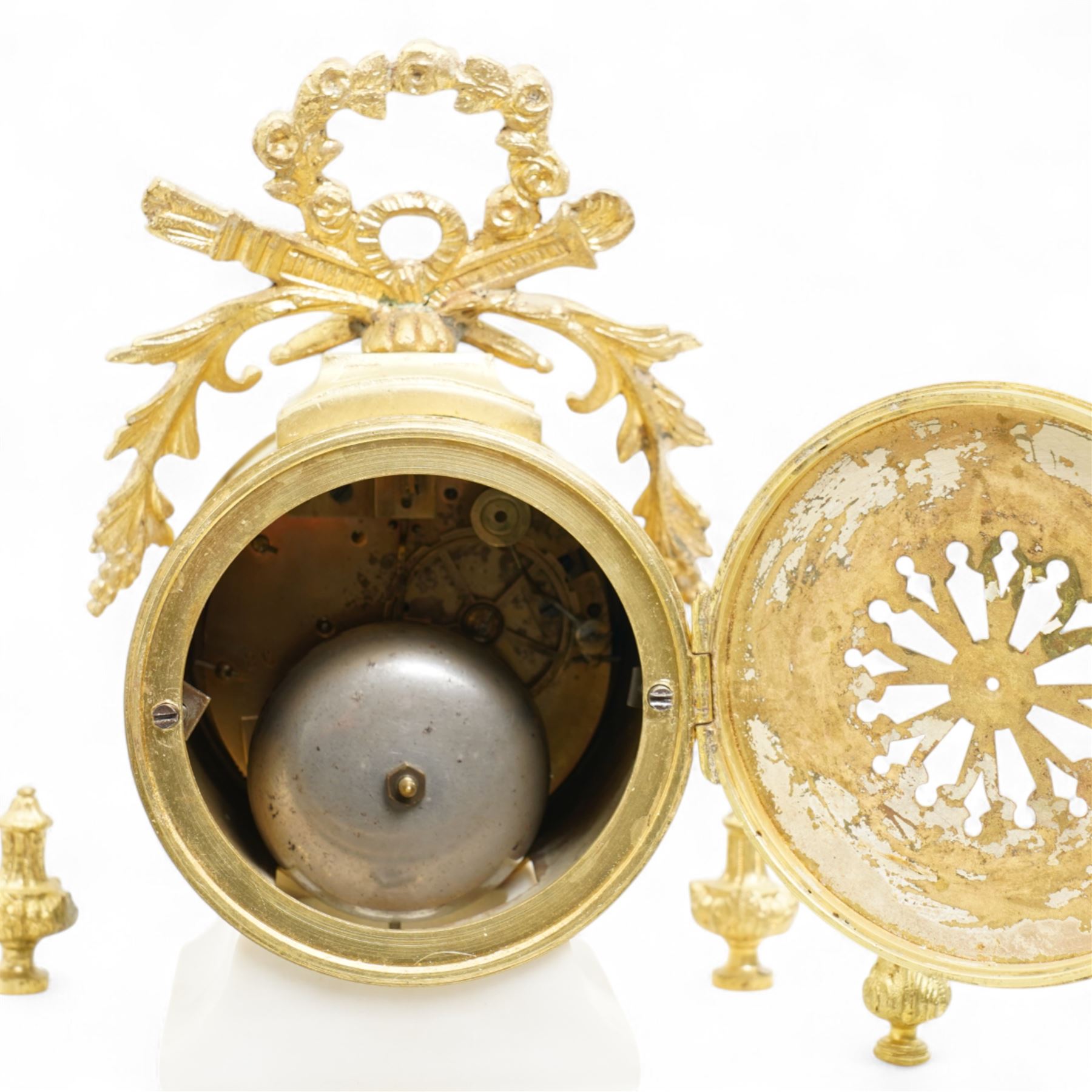 French-Early 20th century 8-day white marble and gilt metal striking portico mantle clock and garniture, Parisian drum movement with a white enamel dial, Arabic numerals and garland swags, two train countwheel striking movement sounding the hours and half hours on a bell. With a matching pair of conforming urns with gilt mounts. 