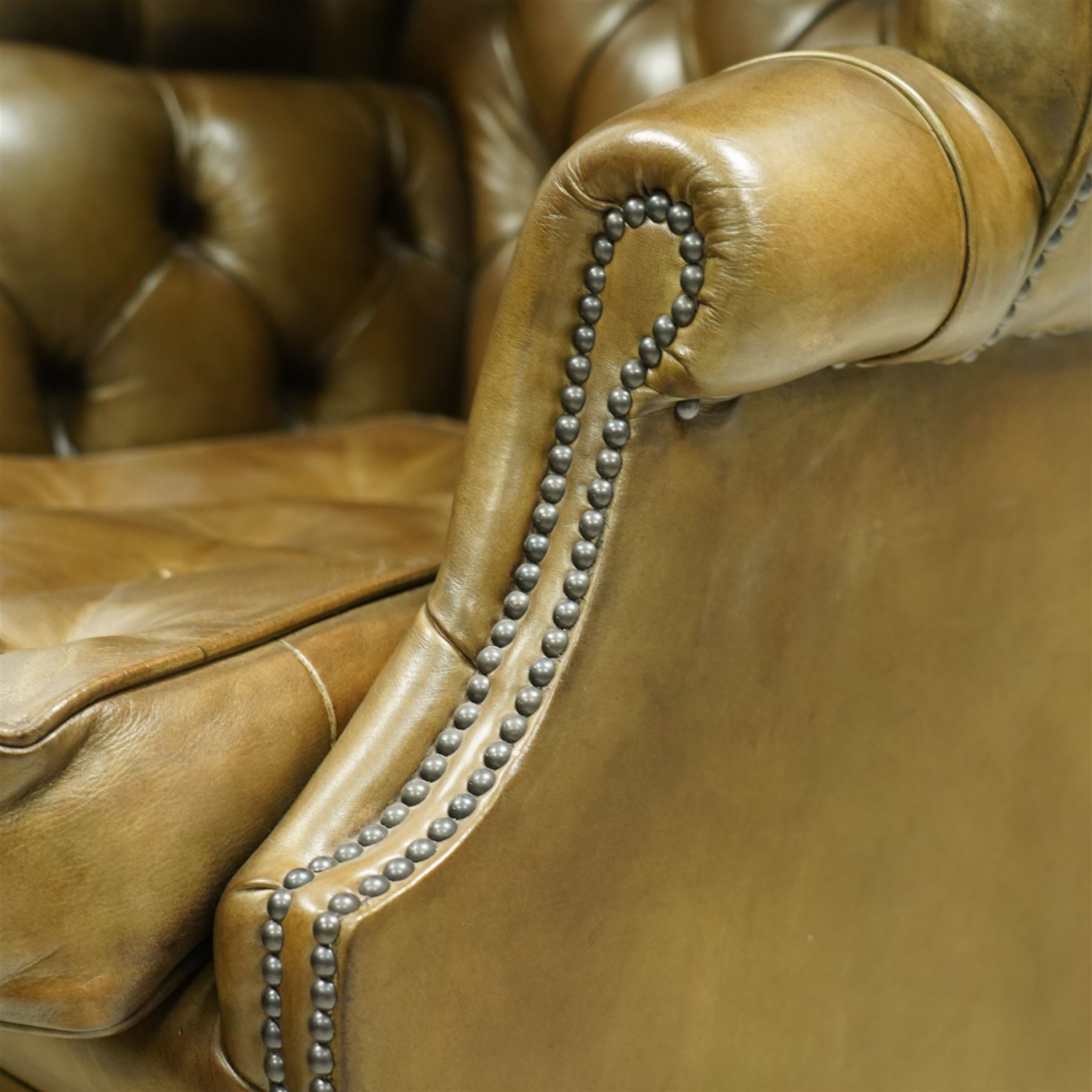 20th century George II style leather upholstered hall porters chair, brass studded upholstered with piping in leather on all sides, the inside top back arms and seat are all pleated and deep buttoned, with removable seat pad, on castors
