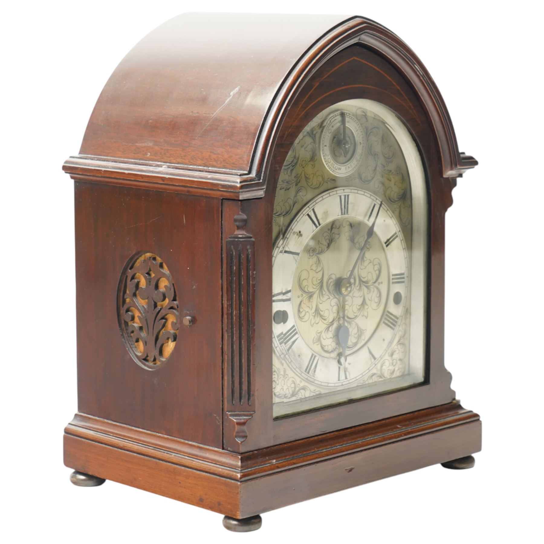 English-8-day 20th-century three train Westminster Chime Lancet clock in a mahogany case, with canted reeded quarter columns to the door and silk backed sound frets to the sides, fully silvered dial with decorative engraving and pendulum adjustment dial, silvered chapter with Roman numerals, minute track and spade hands, chiming the quarters and hours on five coiled gongs, With key, no pendulum. 
