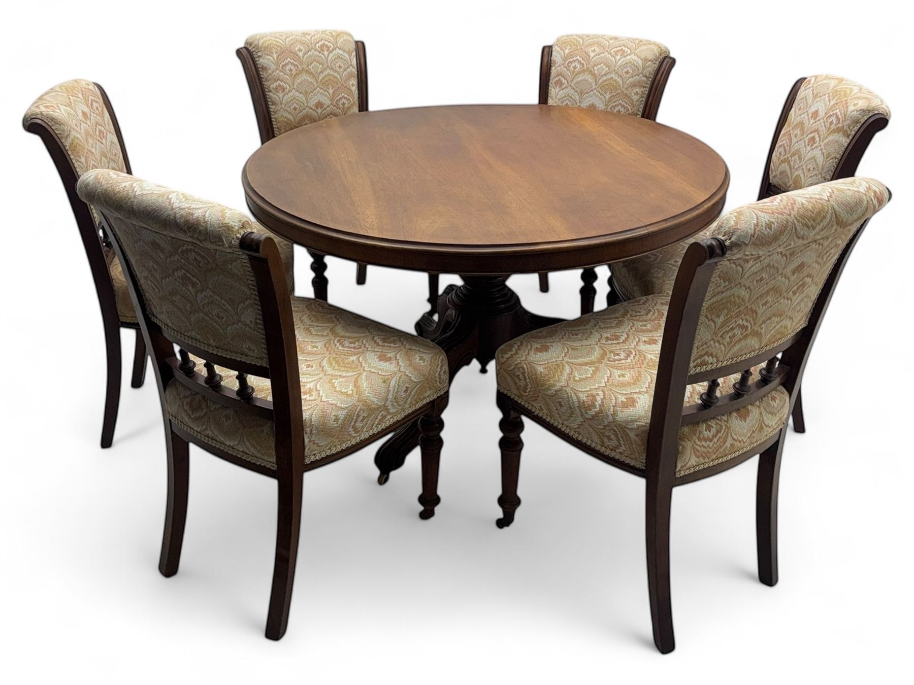 Victorian mahogany centre table, circular top above turned pedestal, terminating on three cabriole legs with scroll feet on porcelain castors, and six scroll carved upholstered dining chairs, with cushion and spindle turned backs, centre table  118x74cm, dining chairs 89x46x50cm
