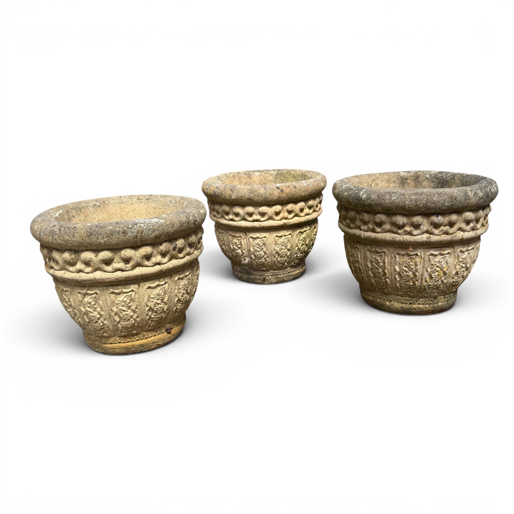 Set of three cast stone planters, circular form with C-scroll design frieze over a floral decorated body, weathered finish