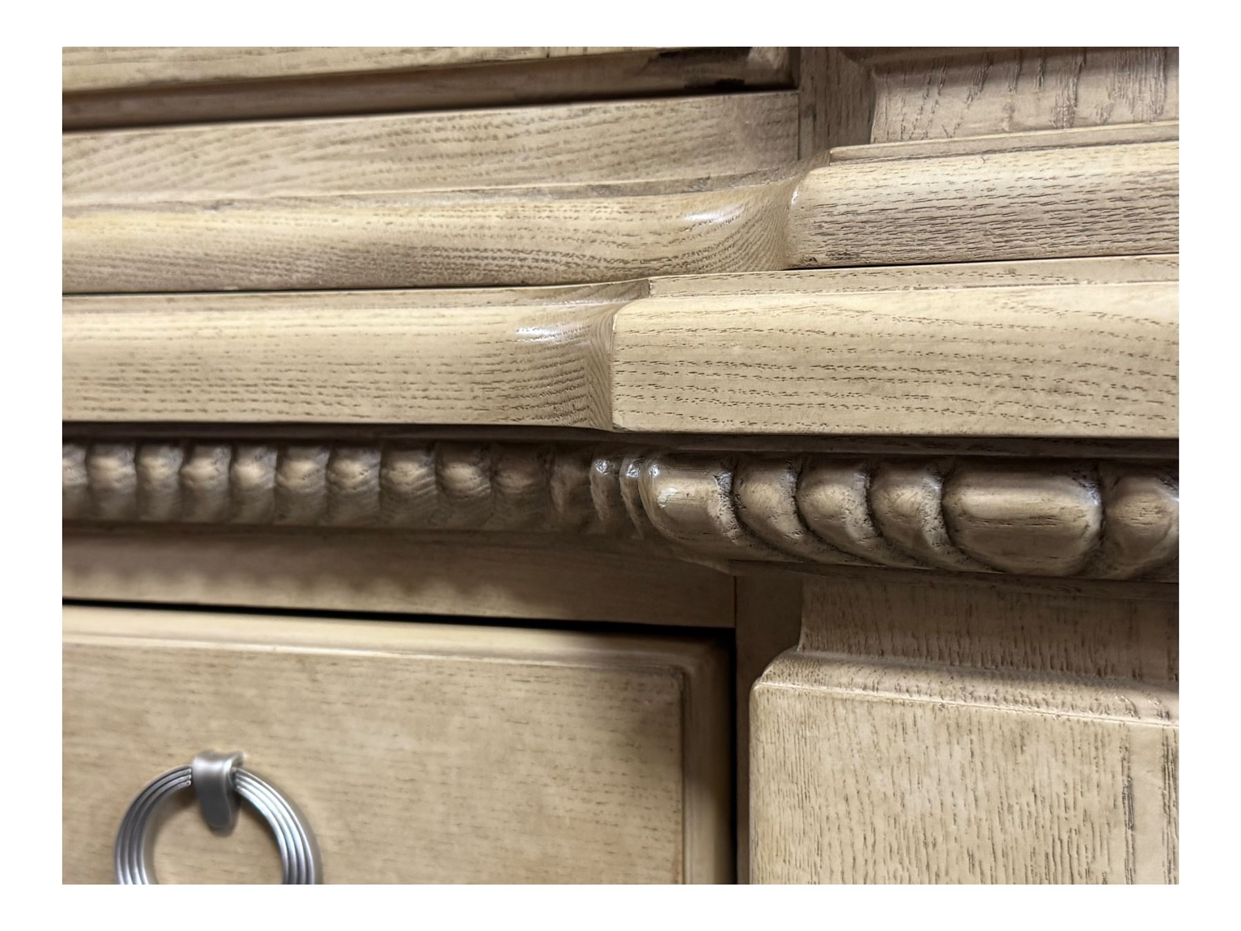 Brunswick - washed oak finish illuminated display cabinet, upper section with four glass-panelled doors enclosing glass shelving, base fitted with two drawers over four paneled cupboard doors, each fitted with distinctive round metal handles, raised on plinth base