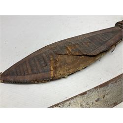 Mandingo sword, the 63cm plain curving steel blade marked with a horses head and the initials G.S.; leather covered grip with metal ribbed spherical pommel; in decorative leather leaf scabbard mounted with tassels and roundels L84cm overall; and a North African flyssa sword in poor condition with wooden scabbard (2)