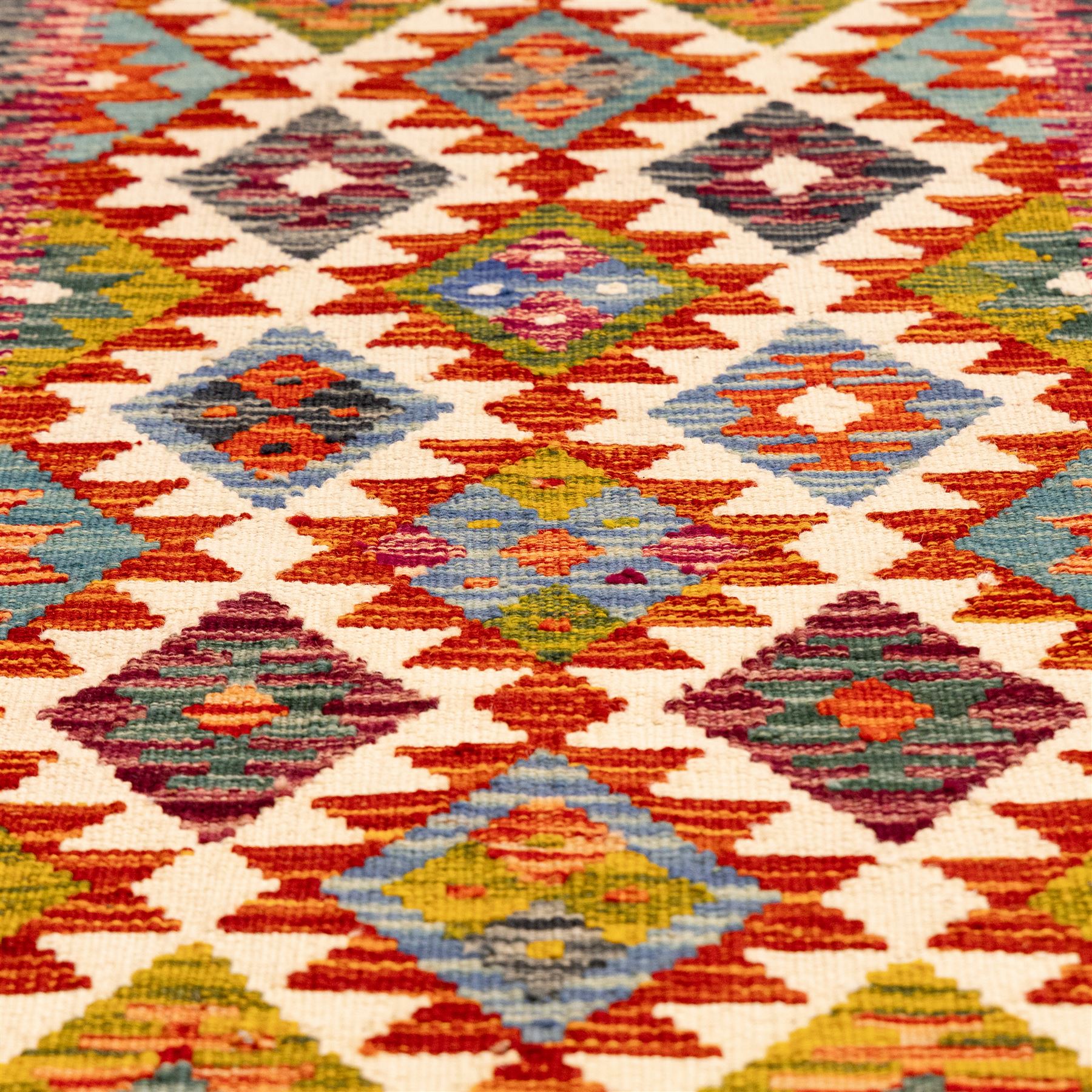 Afghan Chobi flatweave kilim runner, with a repeating stepped diamond medallion design in ivory, green, rust, teal, purple, indigo, and framed by chevron and geometric borders