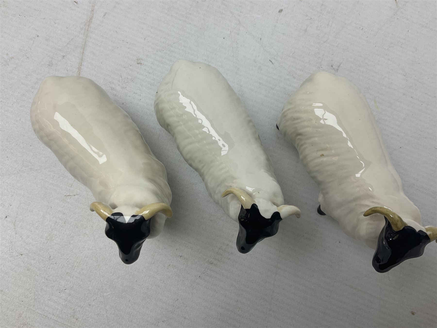 Seven Beswick figures of sheep comprising three ewes and four lambs, together with a figure of a sheepdog (8)