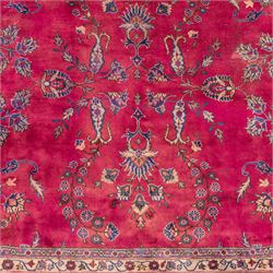 Large Persian-style mahal-type hand-knotted carpet, of rectangular form with a deep crimson field decorated with an all-over arrangement of stylized floral sprays and palmettes, with a central subtle medallion composition enclosed by a dark navy main border of scrolling floral motifs between narrow guard stripes with fringe ends 
