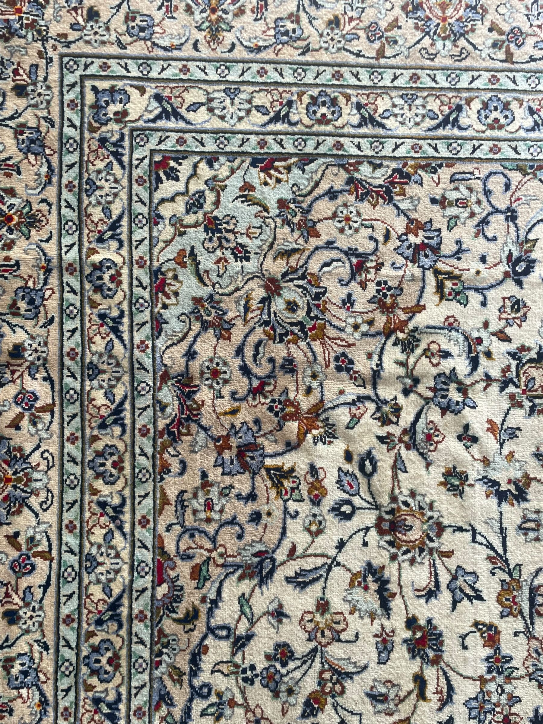 Persian Kashan ivory ground carpet, the field decorated with interlacing foliate branches and stylised plant motifs, scrolling border decorated with repeating palmettes, within floral pattern guard bands