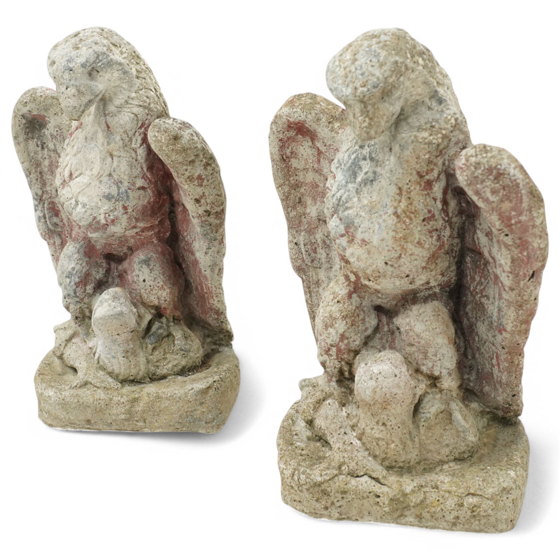 Pair of early 20th century painted stoneware eagle figures, modelled with wings partially spread and talons gripping prey, on a stone plinth