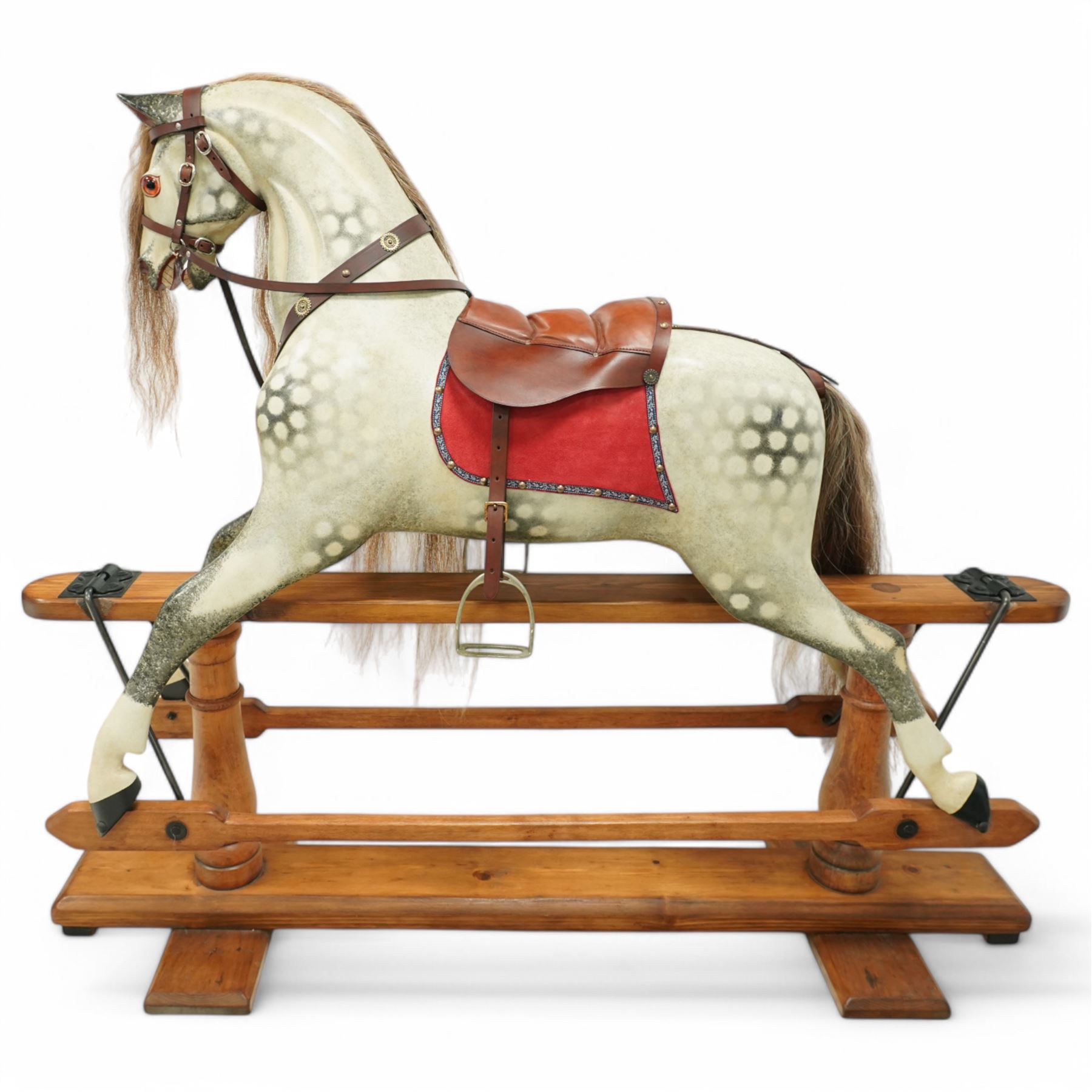 Frederick Henry Ayres (F H Ayres, London) - Late Victorian large carved wooden rocking horse, in dapple grey paint finish, decorated with glass eyes, leather reins, stirrup and saddle, indented hooves, on rockers united by chamfered stretchers and boarded base, c.1890