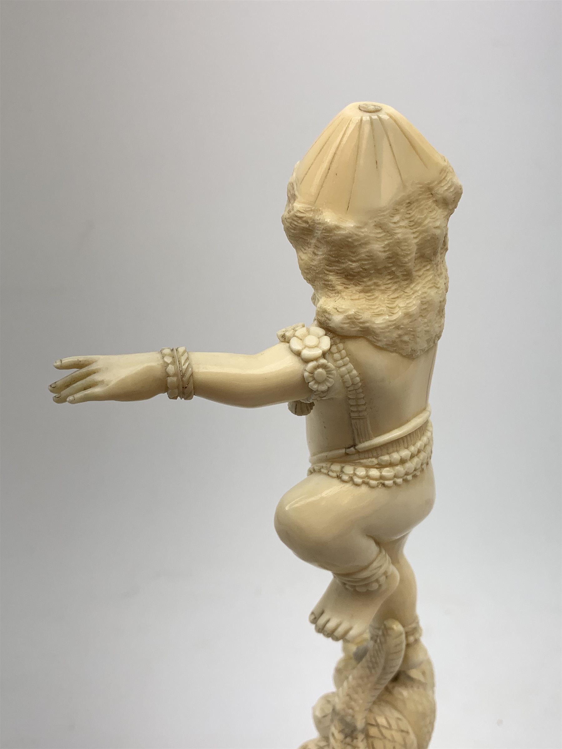 A large Japanese carved ivory okimono, modelled as a figure stood upon one leg with arms outstretched, upon a five headed serpent emerging from waves, H30cm.