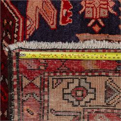 North West Persian runner, the indigo field decorated with three stepped cruciform medallions alternating with two octagonal panels, interspersed with stylised flowerheads and foliage, enclosed by an ivory ground floral border and red guard bands