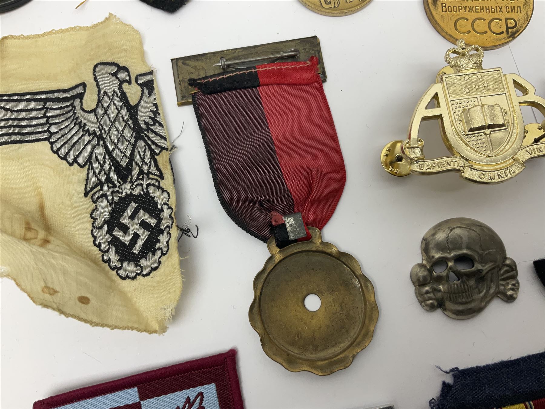 Collection of approximately sixty worldwide medals, metal badges, belt buckles, cloth badges, trench art, brass button stick etc