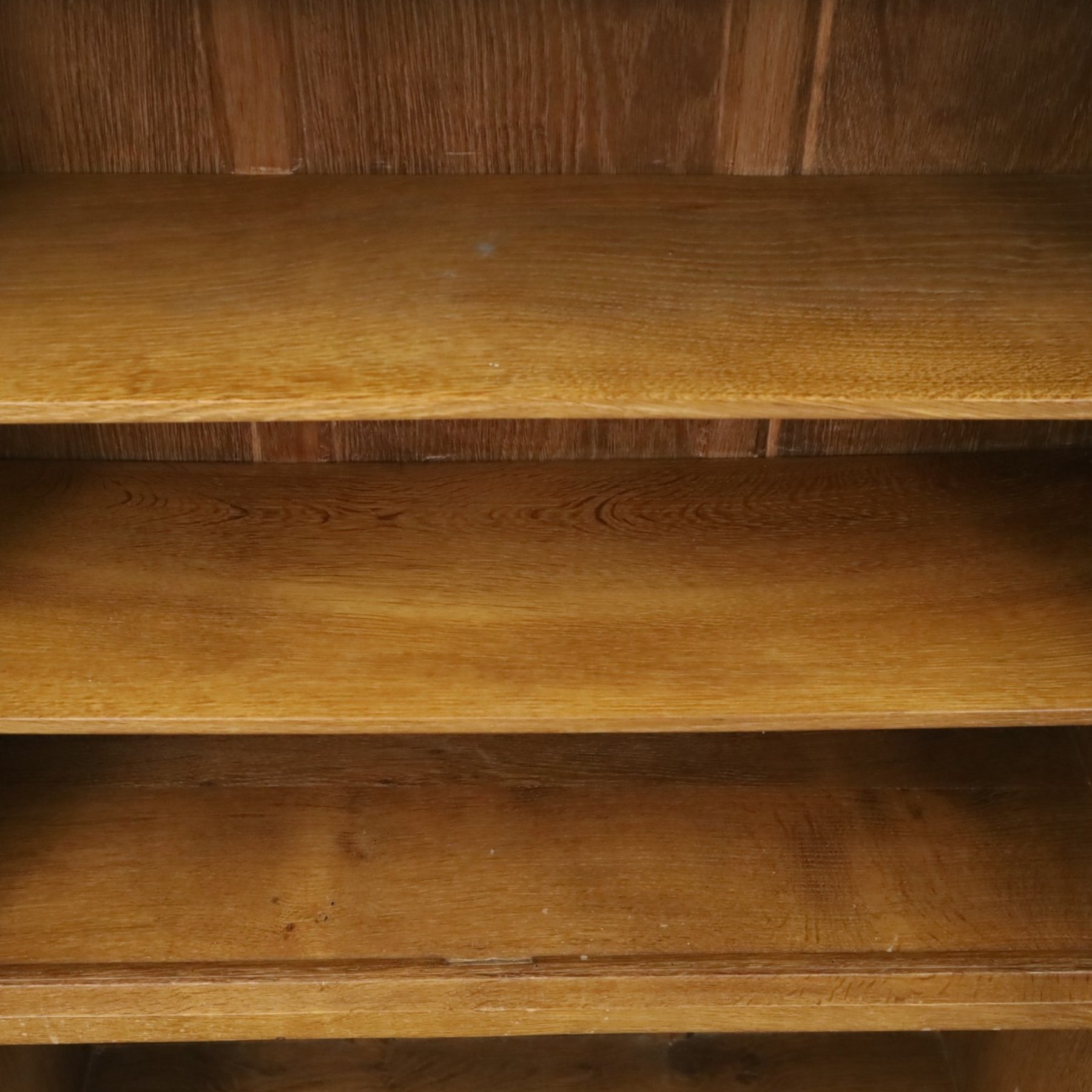 Rabbitman - oak glazed bookcase or display cabinet, lightly adzed rectangular top with raised gallery, twin glazed doors enclosing two shelves, over a pair of panelled cabinet doors with wrought iron fittings, with carved rabbit signature, by Peter Heap of Wetwang