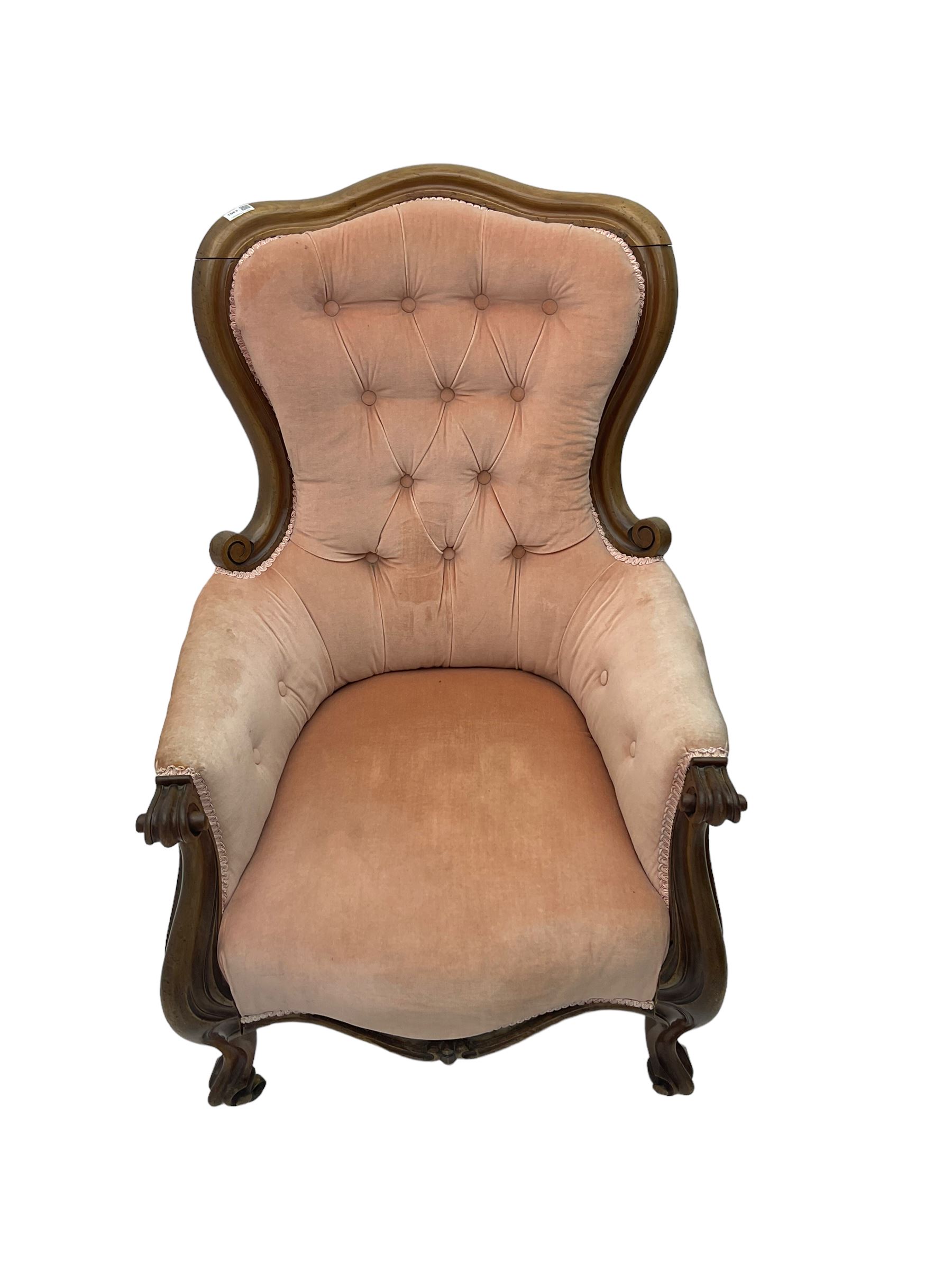 Victorian walnut framed armchair, shaped back with carved and scrolled arm terminals, upholstered in buttoned pale pink fabric, raised on cabriole supports terminating in castors