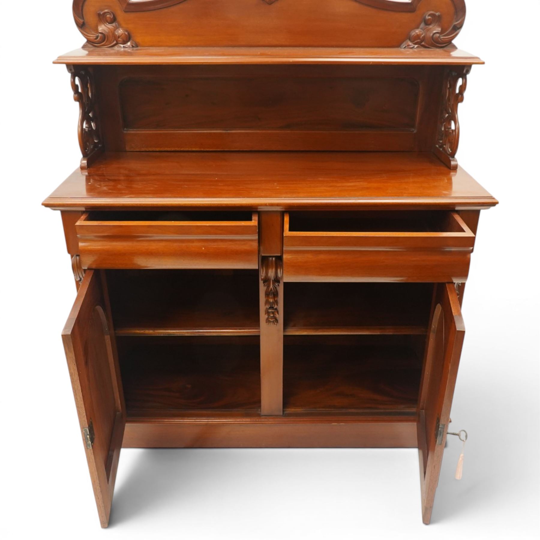 Victorian mahogany chiffonier, the superstructure with shaped back and pierced side supports above a shelf, moulded top over twin arched panel doors enclosing cupboard interior, with carved scroll brackets, on plinth base