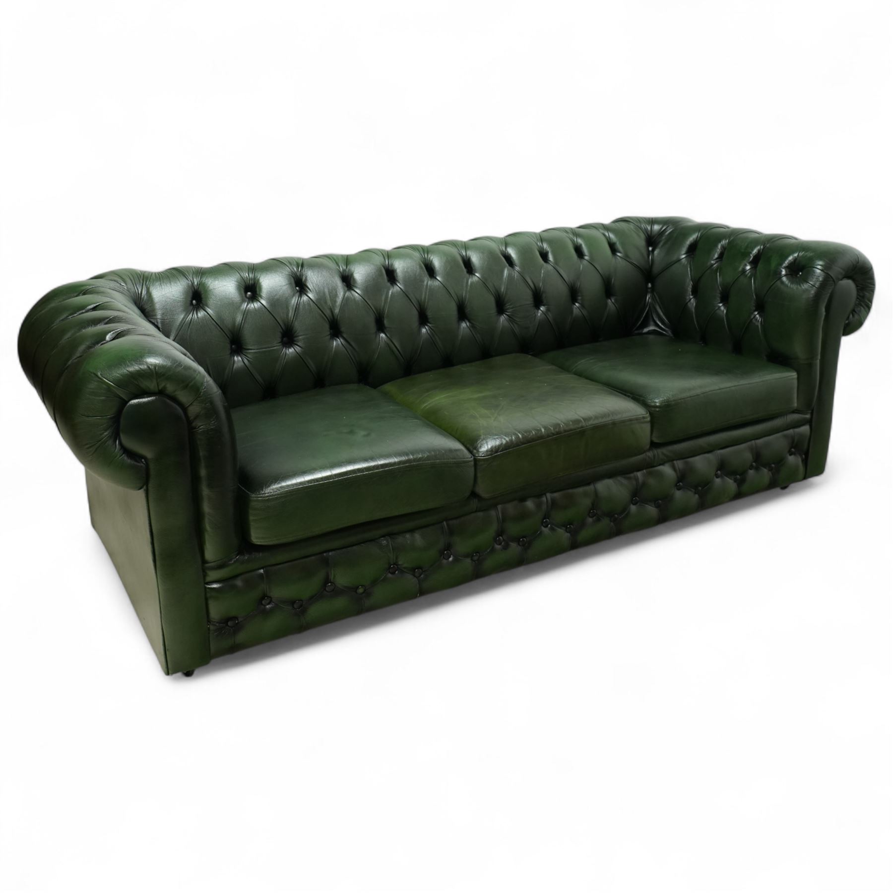 Late 20th century chesterfield style sofa upholstered in green leather, with deep buttoned back and arms above three loose cushions, continuous scroll arms and front, on concealed block feet