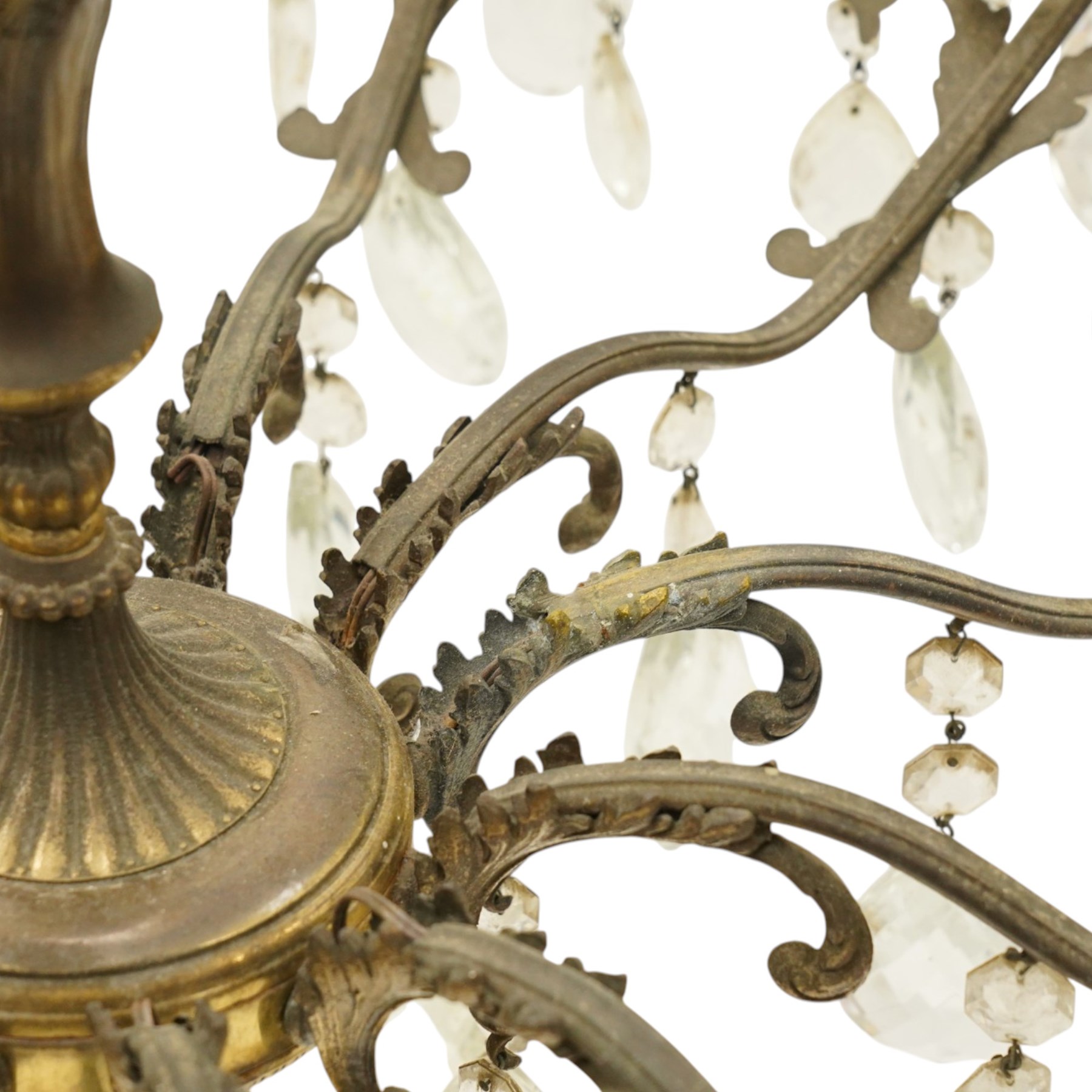 20th century Louis XV design gilt and patinated metal twelve-light chandelier, the foliate-cast baluster stem issuing scrolling acanthus branches with leaf-form drip pans, hung throughout with faceted glass pendants and lustre drops, suspended from chains beneath a foliate ceiling rose