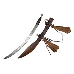 Mandingo sword with 63cm plain curving steel blade and leather covered grip with white metal ribbed spherical pommel; in decorative leather leaf scabbard with plaited tassels and shoulder strap L78cm overall
