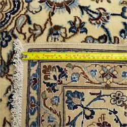 Central Persian Nain hand-knotted carpet, ivory ground, with silk highlights, centred by a shaped floral medallion with pendants, surrounded by scrolling foliate and floral motifs incorporating rosettes, palmettes and delicate vine work in blue, cream and beige tones, enclosed by blue spandrels and an ivory border with repeating palmettes and meandering vines, flanked by floral guard stripes, with cotton fringes
