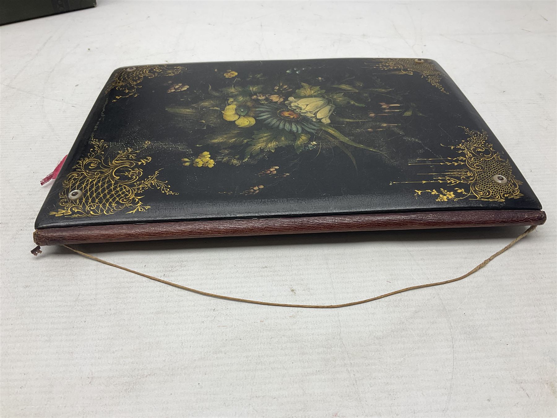 Victorian desk ink blotter, decorated with painted spray of flowers within stylised gilt rococo spandrels with mother of pearl fixings, together with a Victorian photo album containing interior leaves with apertures of various sizes and shapes of portraits surrounded by printed sea and dock scenes, blotter L28cm