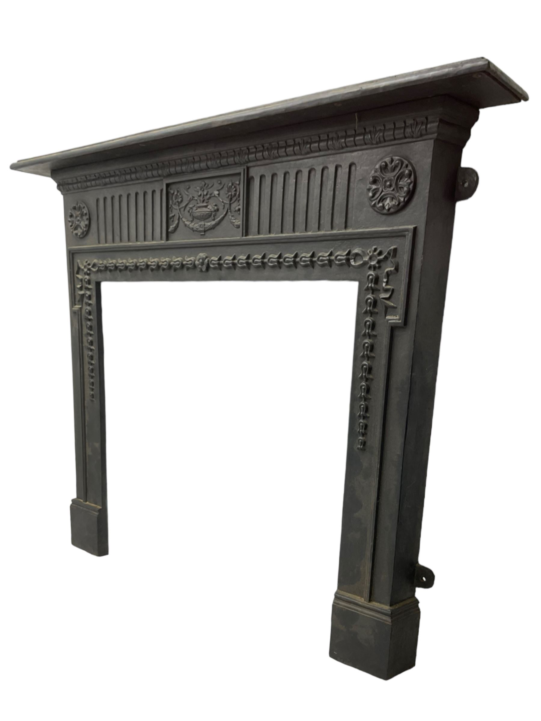 Adam design - cast iron fire surround, moulded rectangular mantel over central foliate urn and vertical flutes, flanked by C-scroll floral roundels, the aperture decorated with trailing bellflowers