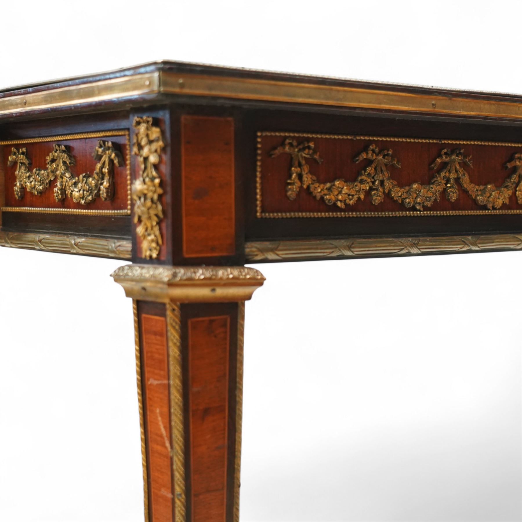 Fine 19th-century Louis XVI-style mahogany and gilt bronze-mounted writing table, rectangular top with a gilt tooled tan leather writing surface within a moulded gilt bronze edge above a frieze fitted with three drawers, mounted with floral and foliate gilt bronze swags  and borders, raised on square tapering legs with acanthus mounts and toupie feet