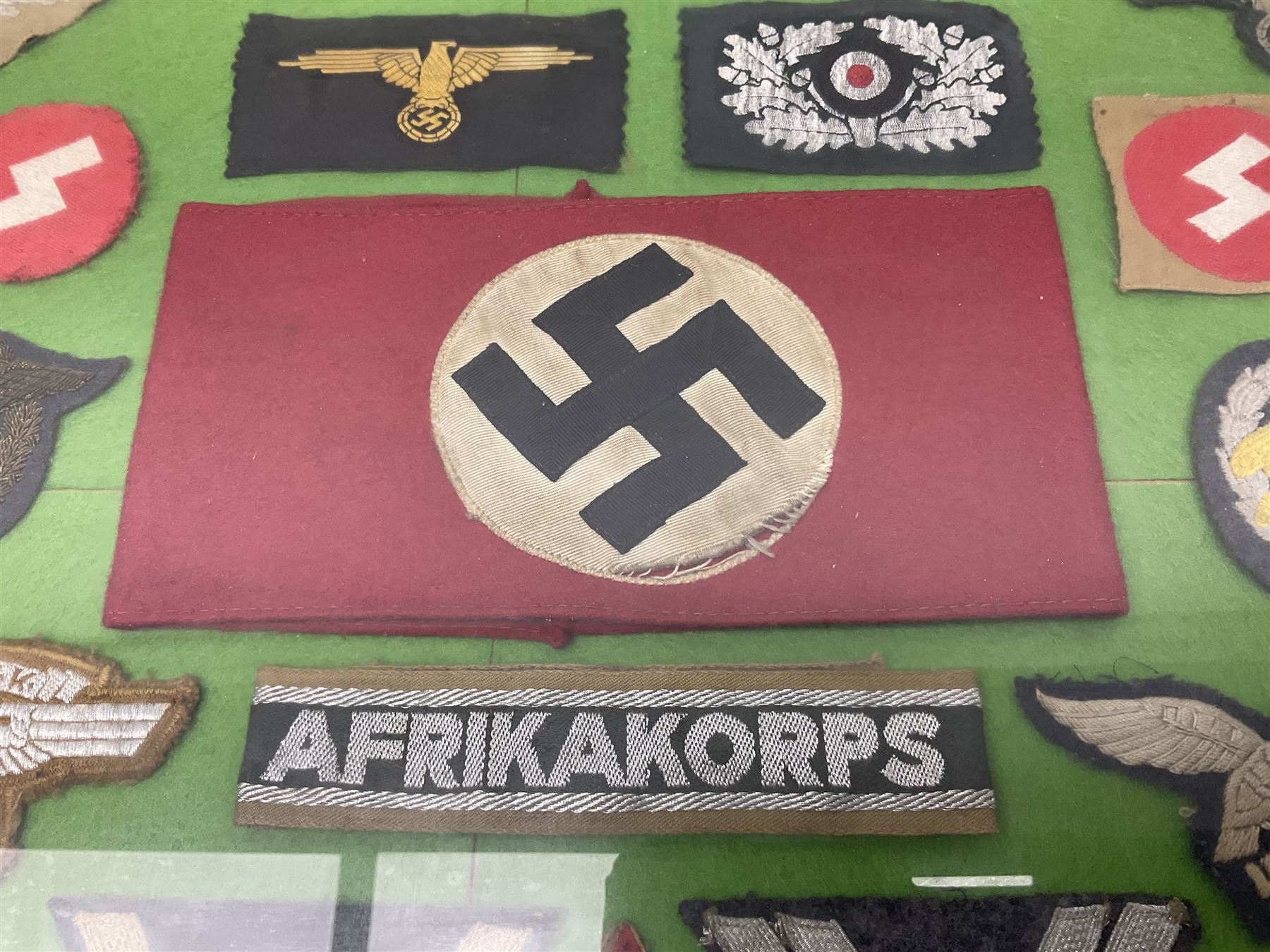 Framed display of thirty-four WWII German cloth badges including Luftwaffe pilot, Paratrooper, Afrikakorps cuff title, sleeve insignia for 'SS' Foreign Volunteers, various breast eagles including Luftwaffe, Army etc, RAD badges, Party Armband, rank and trade insignia, cap insignia etc; 40 x 50cm in modern pine frame