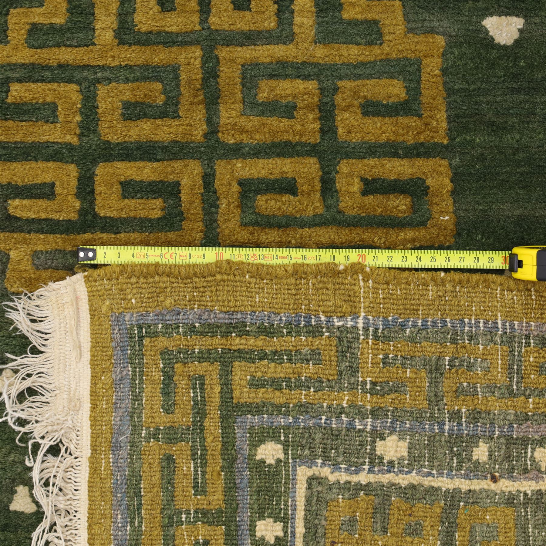 Chinese Ningxia rug, green field with central stylized shou medallion and scattered cloud motifs within key fret borders in shades of olive green, fringe ends partially detached 
