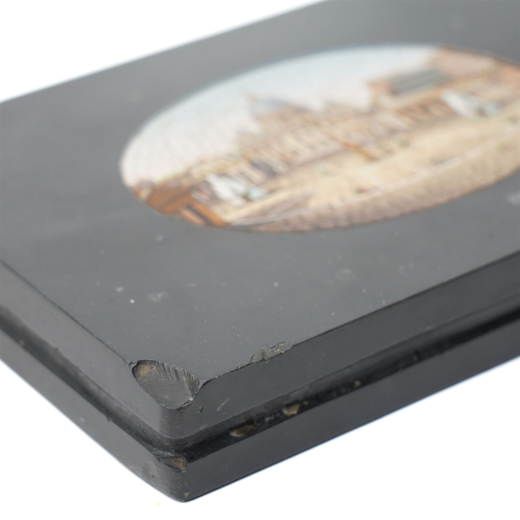 19th-century Italian Grand Tour micromosaic paperweight, the rectangular slab of polished Nero Belgio black marble inset with an oval micromosaic panel finely composed in minute tesserae, depicting a classical architectural view evocative of ancient Rome, centred by a triumphal column and flanked by monumental buildings, 14cm x 9.5cm
