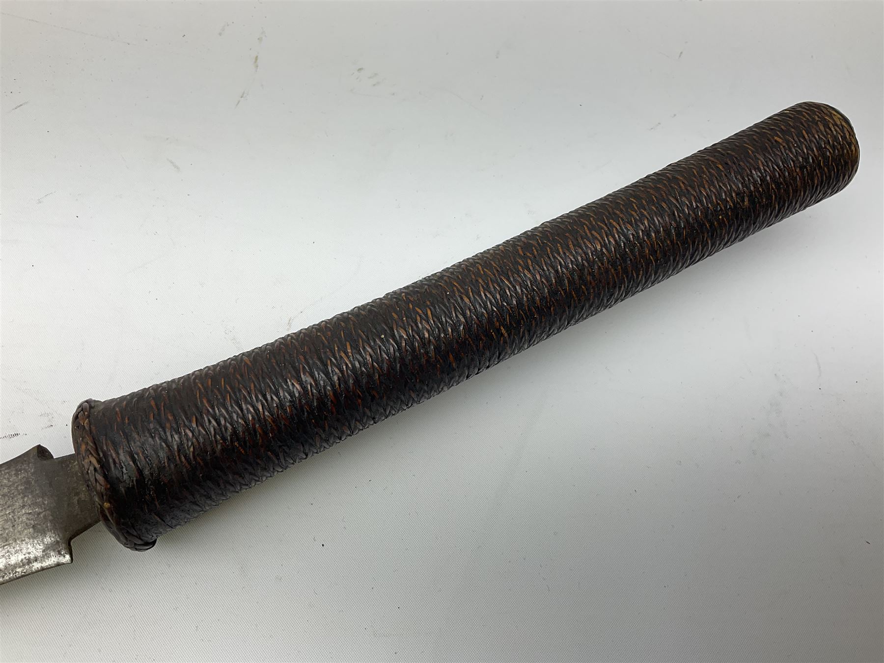 Burmese Dha type sword with 52cm plain steel slightly curving blade and plaited cane bound grip; in wooden scabbard with plaited cane bands L76.5cm overall