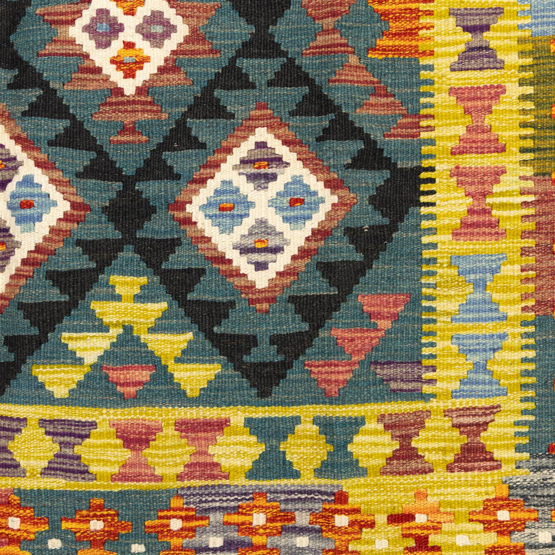 Chobi flatweave kilim with a repeating stepped diamond medallion design in live green, rust, teal, purple, and ivory, framed by chevron and geometric borders