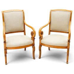 Pair of French Empire design fauteuil armchairs, high back over scrolled arm terminals, upholstered in cream fabric, on scroll carved cabriole supports