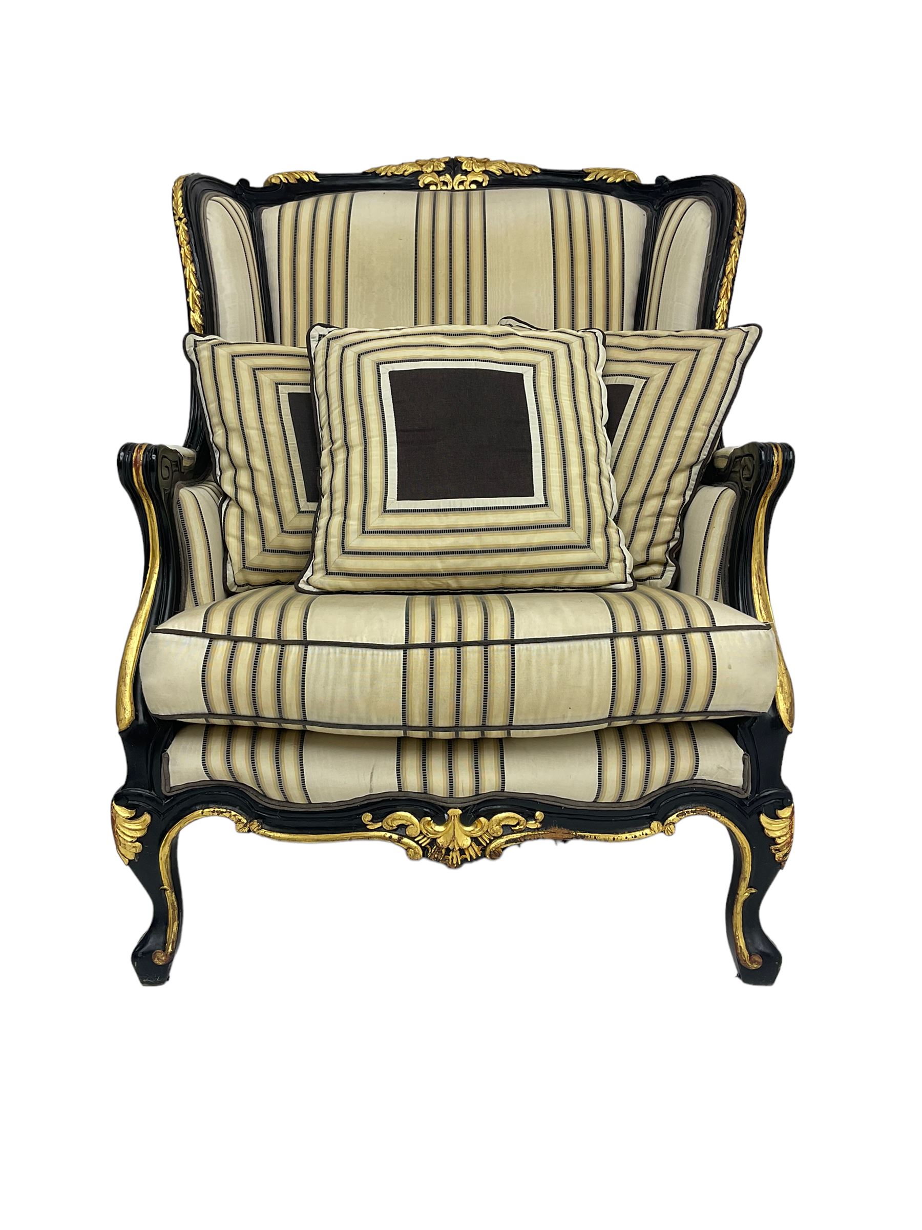 Thomas Messel - Georgian style ebonised and gilt wingback armchair, upholstered in striped fabric, on cabriole front feet