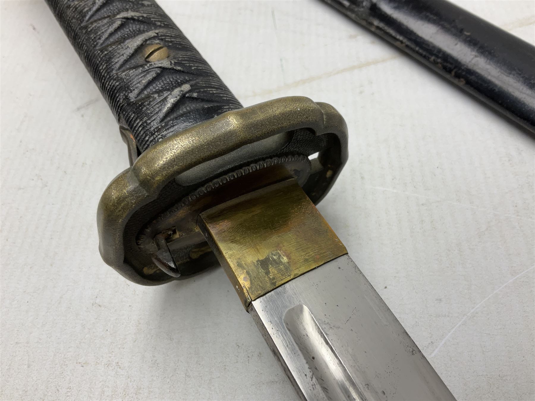WW2 Japanese Army NCOs sword - katana, the 69.5cm slightly curving fullered blade numbered 14656; arsenal markings stamped near the habaki on the handle; brass tsuba and black painted metal hilt cast to simulate cord bound fish skin; in black painted steel scabbard with single suspension ring L96cm overall