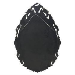 20th century Venetian style oval mirror, the central mirror plate enclosed by an ebonised border decorated with engraved floral trails and dotted reserves, the outer edge applied with shaped and etched glass leaves and scrolling foliage