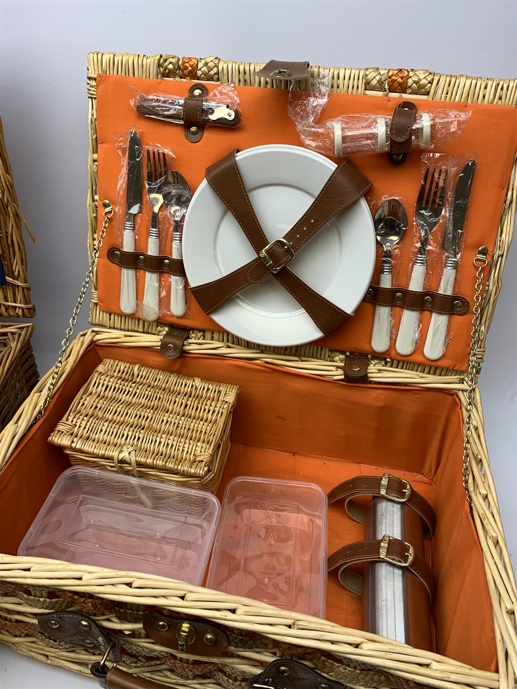  Two wicker picnic baskets, the largest by Optima and fitted for four people, the smaller unmarked and fitted for two, largest when closed H20cm L56 D38.  