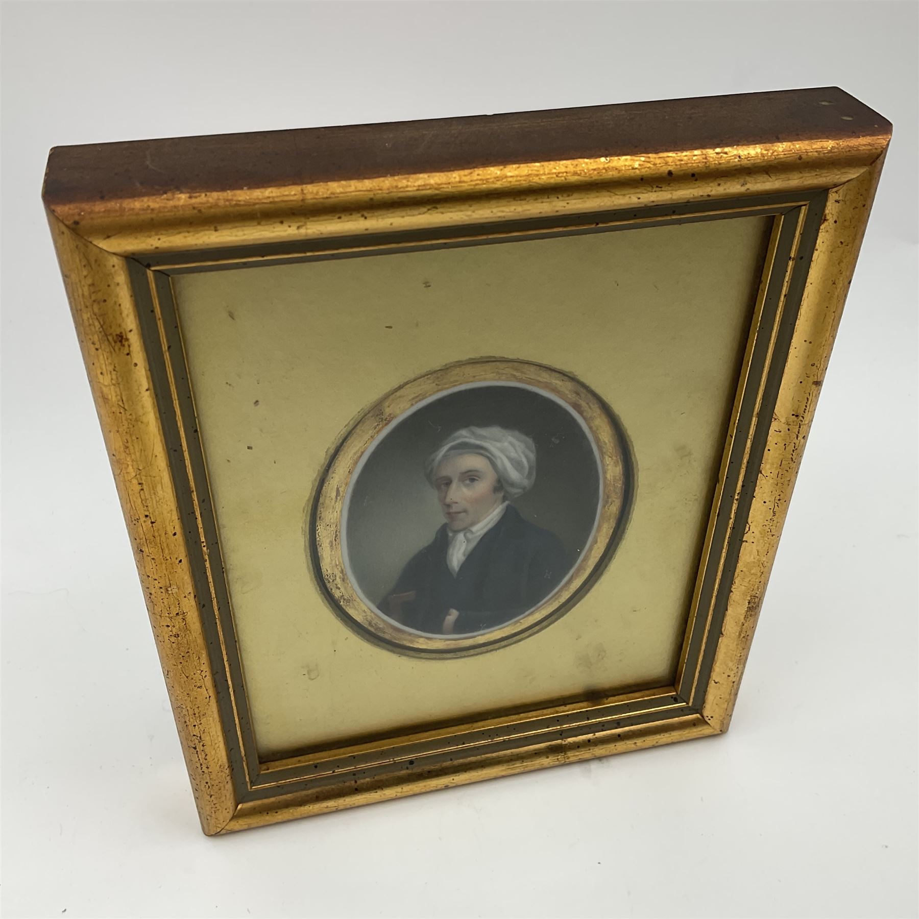 English School (18th century)
Portrait miniature upon ceramic plaque 
Head and shoulder portrait of a gentleman in blue coat and white turban, holding book under one arm
Indistinct inscription verso
Within gilt mount and gilt frame under glass
Portrait 7cm x 5.5cm 
Plaque 14cm x 11.5cm
Frame 16cm x 13.5cm