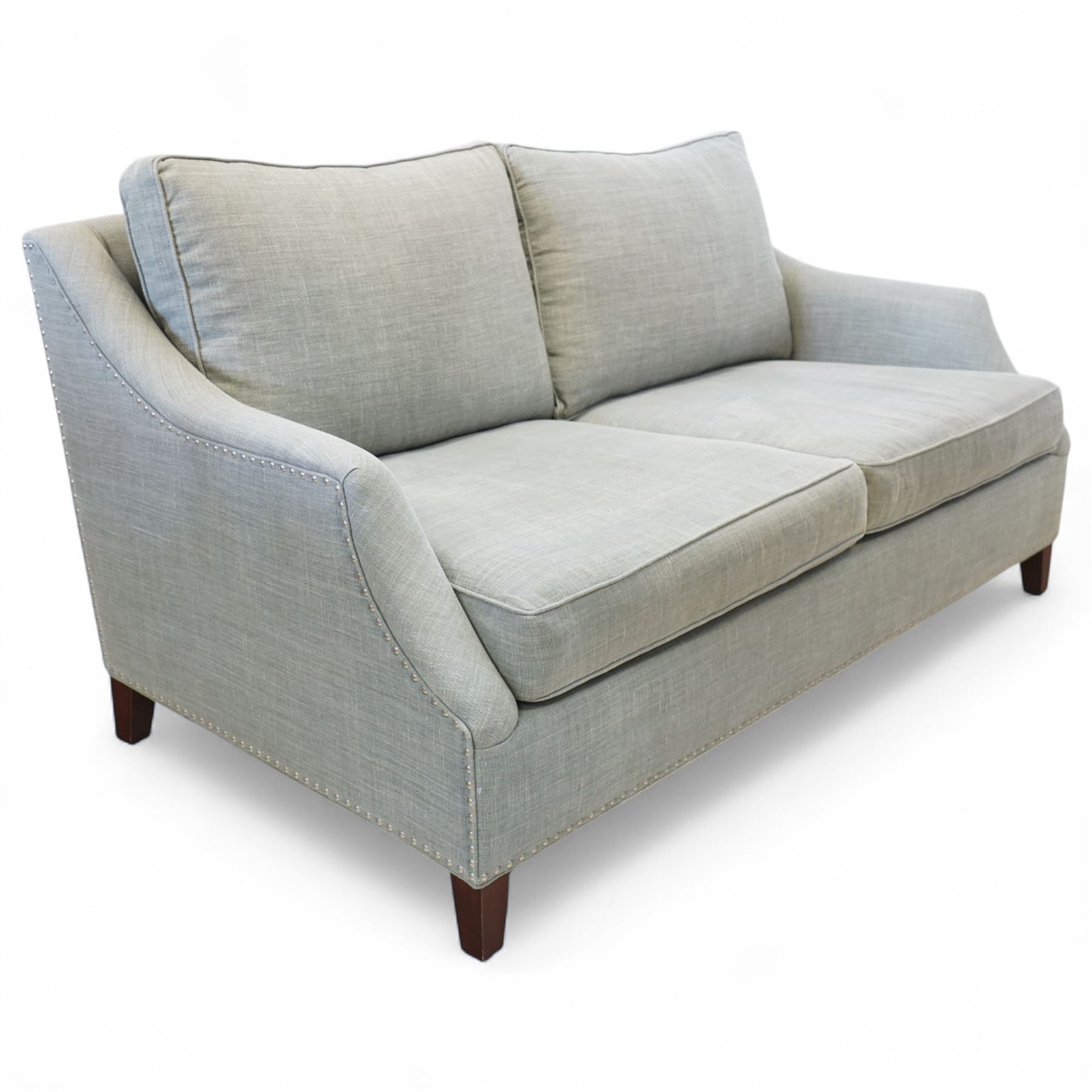 Neptune traditional style two-seat sofa, sloped back rest, gently flared arms, studded upholstered in a light grey fabric on square tapered legs 