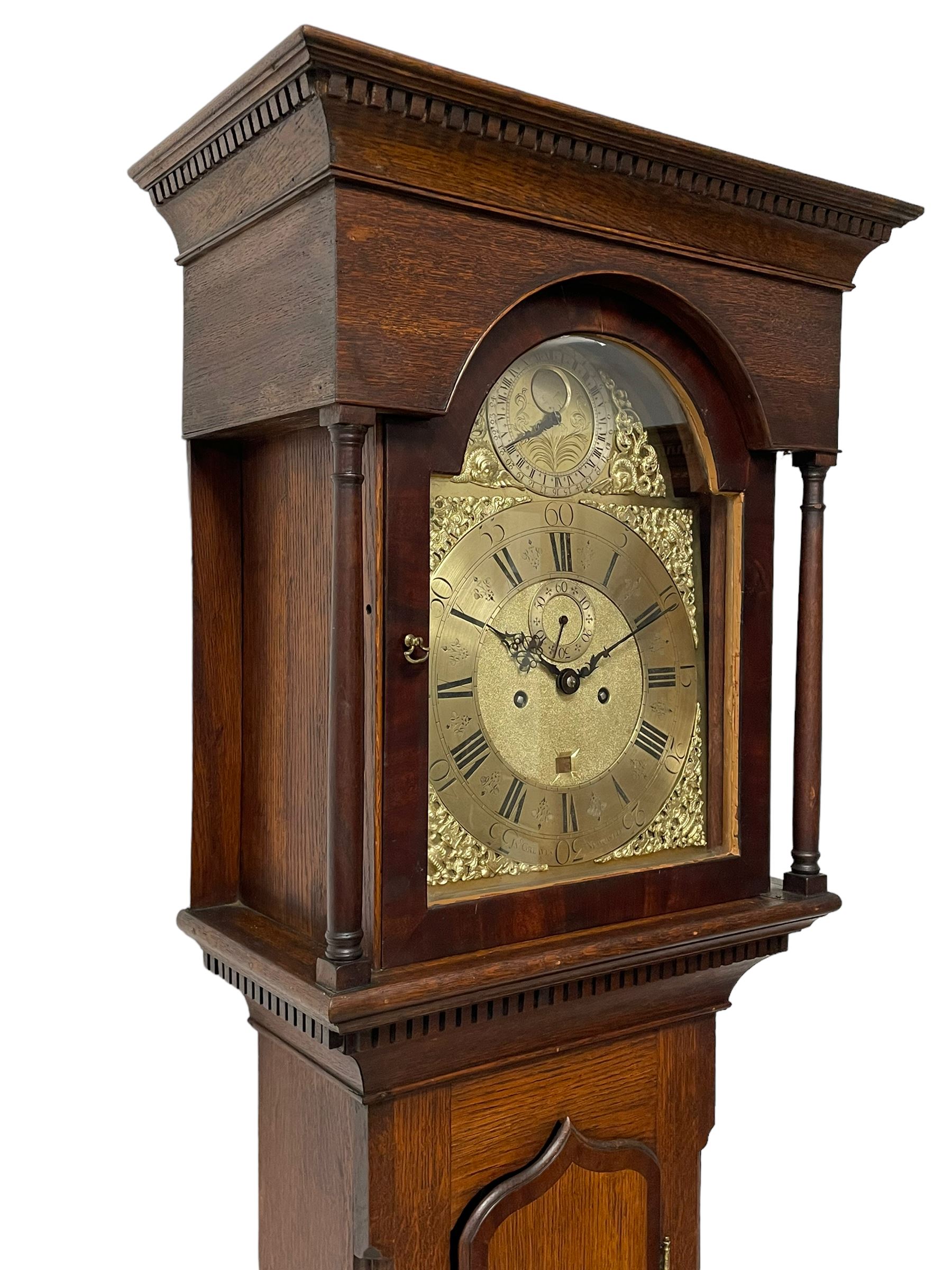 John Greaves of Newcastle - Mid-18th century 8-day oak longcase clock with a flat top, double cornice and break arch hood door flanked by two turned pilasters, trunk with canted corners and a spire topped door with crossbanding, rectangular plinth raised on bracket feet, brass dial with cast spandrels and penny-moon dial and pointer to the arch, matted dial centre with a silvered chapter ring and seconds ring, chapter with Roman numerals, five minute Arabic's, minute and quarter tracks, square date aperture and fettled steel hands, dial pinned to a rack striking movement with a recoil anchor escapement. With pendulum and weights.
