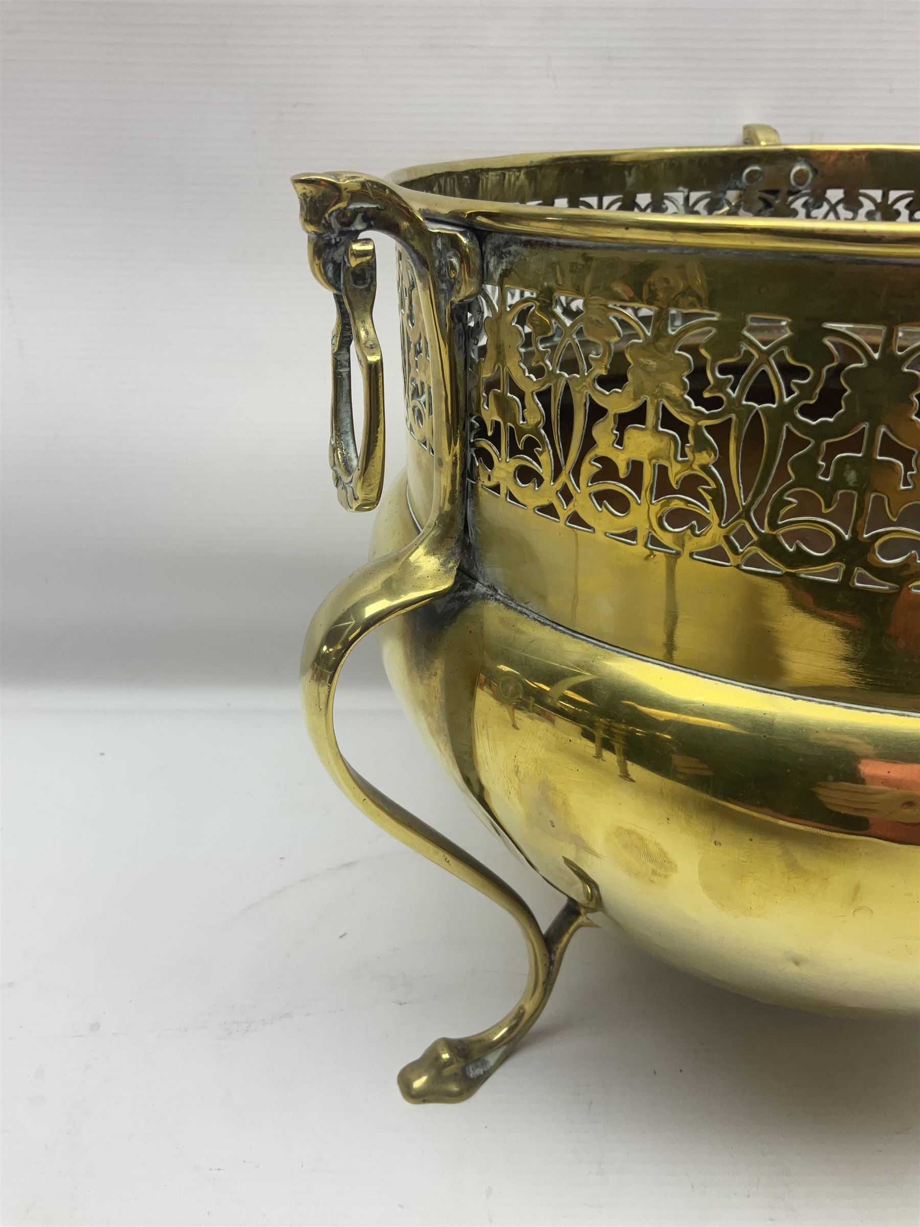 Early 20th century brass coal bucket with pierced sides, upon three pad feet, together with a pair of brass fire dogs, with flambe finials, coal bucket H27cm