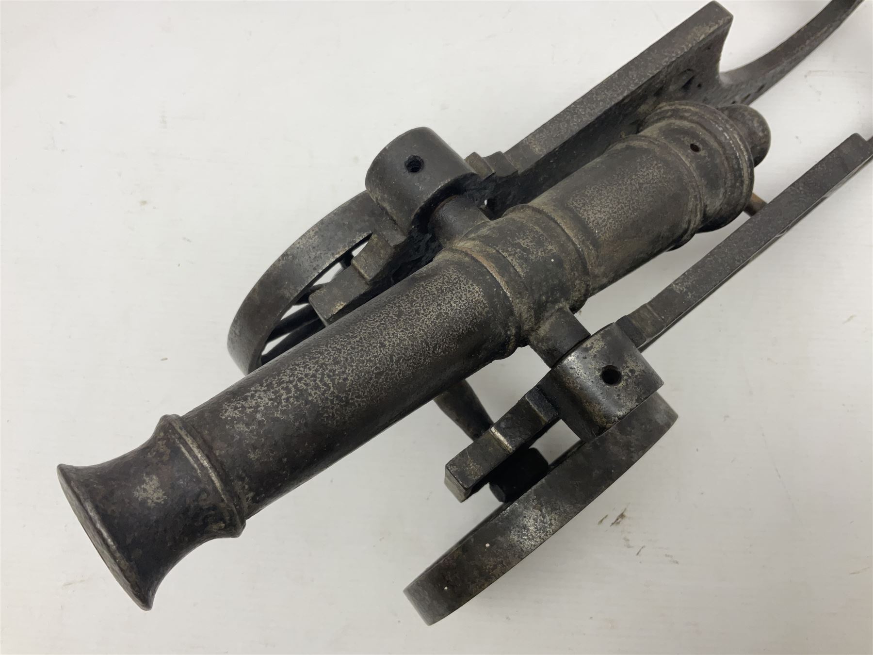 Victorian cast-iron and steel signal cannon, approximately half-inch bore, with 23cm ringed barrel and cylindrical trunnions, on a cast iron carriage with two twelve-spoked wheels and guilloche pierced swept back support, L43cm overall
