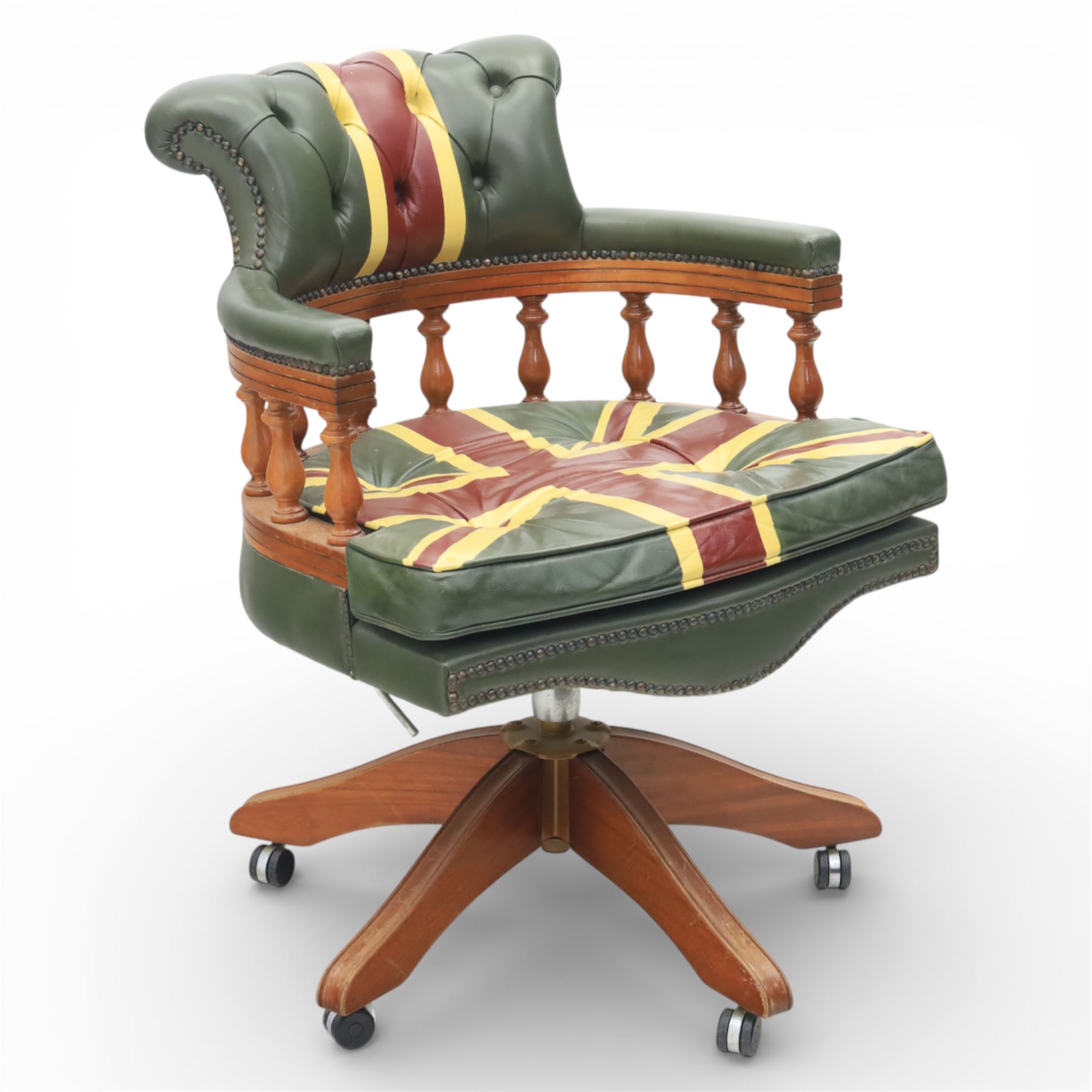 Late 20th century captain’s swivel desk chair, button upholstered back and seat in green leather with Union Jack motif panels, brass stud edging, curved padded arms with turned spindle supports, revolving and height adjustable action, on a five branch wooden base with castors