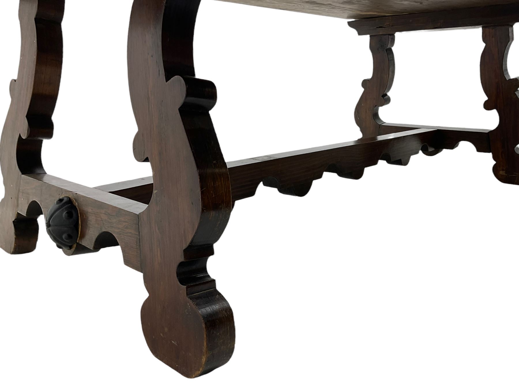 Large Spanish hardwood dining table, on shaped open ends supports joined by stretcher 
