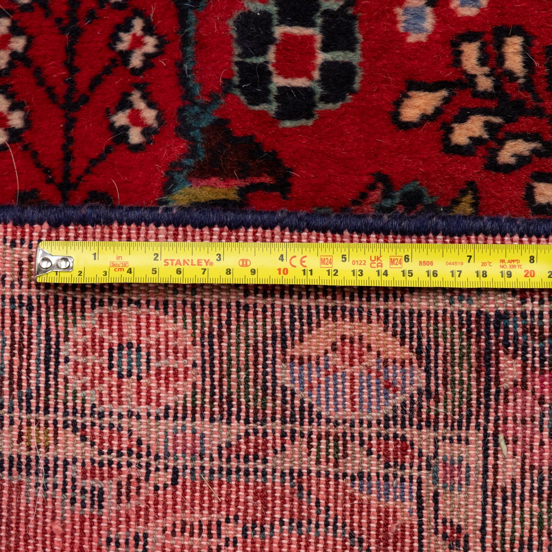 Two Persian rugs, the larger with a crimson field decorated with three linked indigo medallions amongst flowering tendrils, shaped floral spandrels and an indigo palmette border, (161cm x 129cm), the smaller with a crimson field centred by an ivory rosette amongst stylised flowering plants, within a dark floral border, (114cm x 79cm) (2)