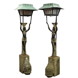  Pair architectural entrance lanterns, black and silver painted cast iron semi-nude Egyptian Goddess holding wrought metal lantern with canopy, mounted on carved and stepped stone gate post finials, H202cm  