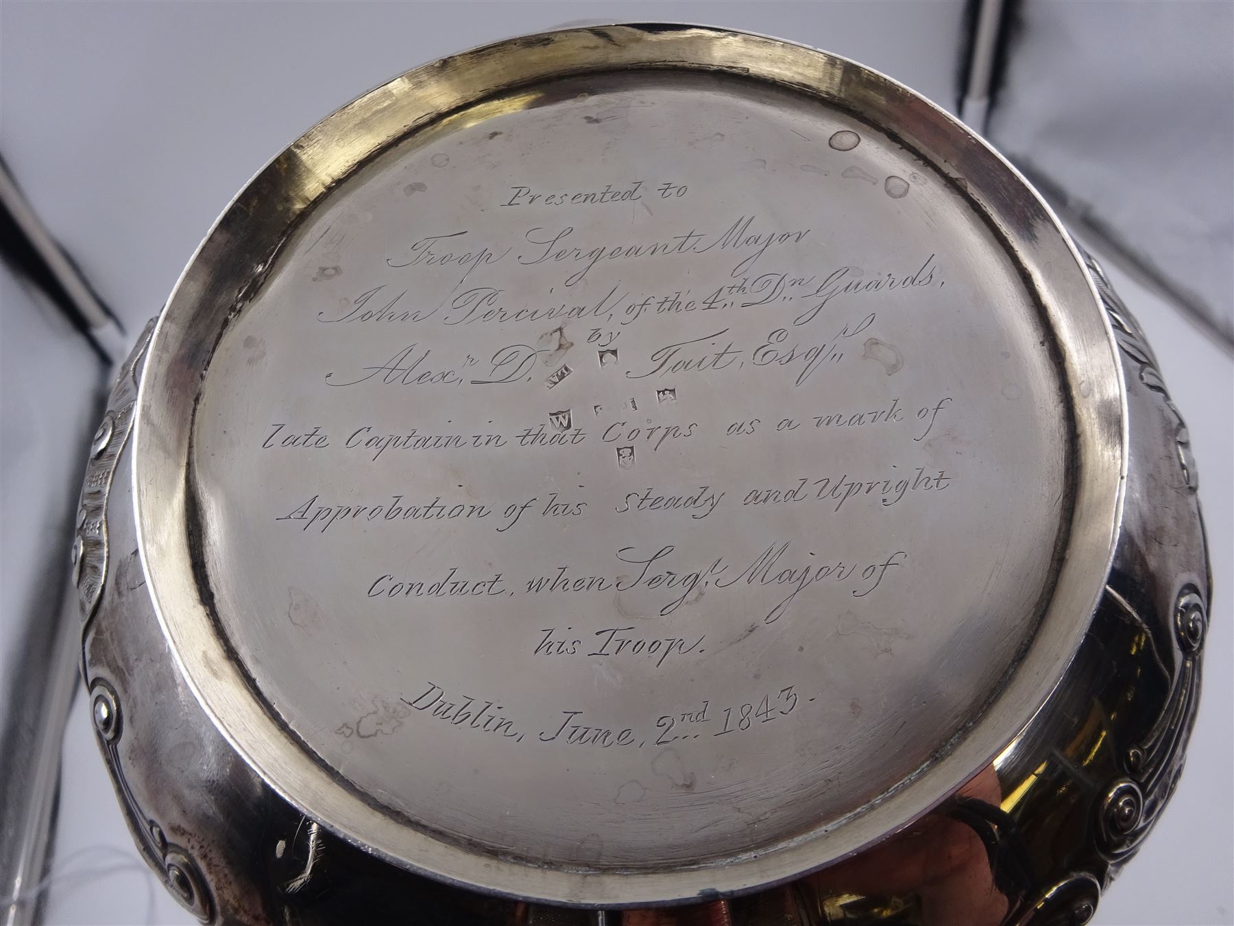 George III Irish silver teapot, of squat circular form, the body with repousse and chased floral and C scroll decoration, with capped C handle and ivory insulators, engraved to base 'Presented to Troop Sergeant Major John Percival, of the 4th Dragoon Guards by Alex D. Tait, Esq, late Captain in that corps as a mark of approbation of his steady and upright conduct when Sergeant Major of his Troop, Dublin, June 2nd 1843', hallmarked William Law, Dublin 1817, H12.5cm, This item has been registered for sale under Section 10 of the APHA Ivory Act