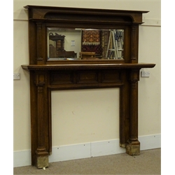  Edwardian oak fire-surround, raised bevel edge mirror back, projecting moulded cornice above single shelf with dentil frieze, two reeded columns flanking central aperture, W190cm, H217cm, D37cm  